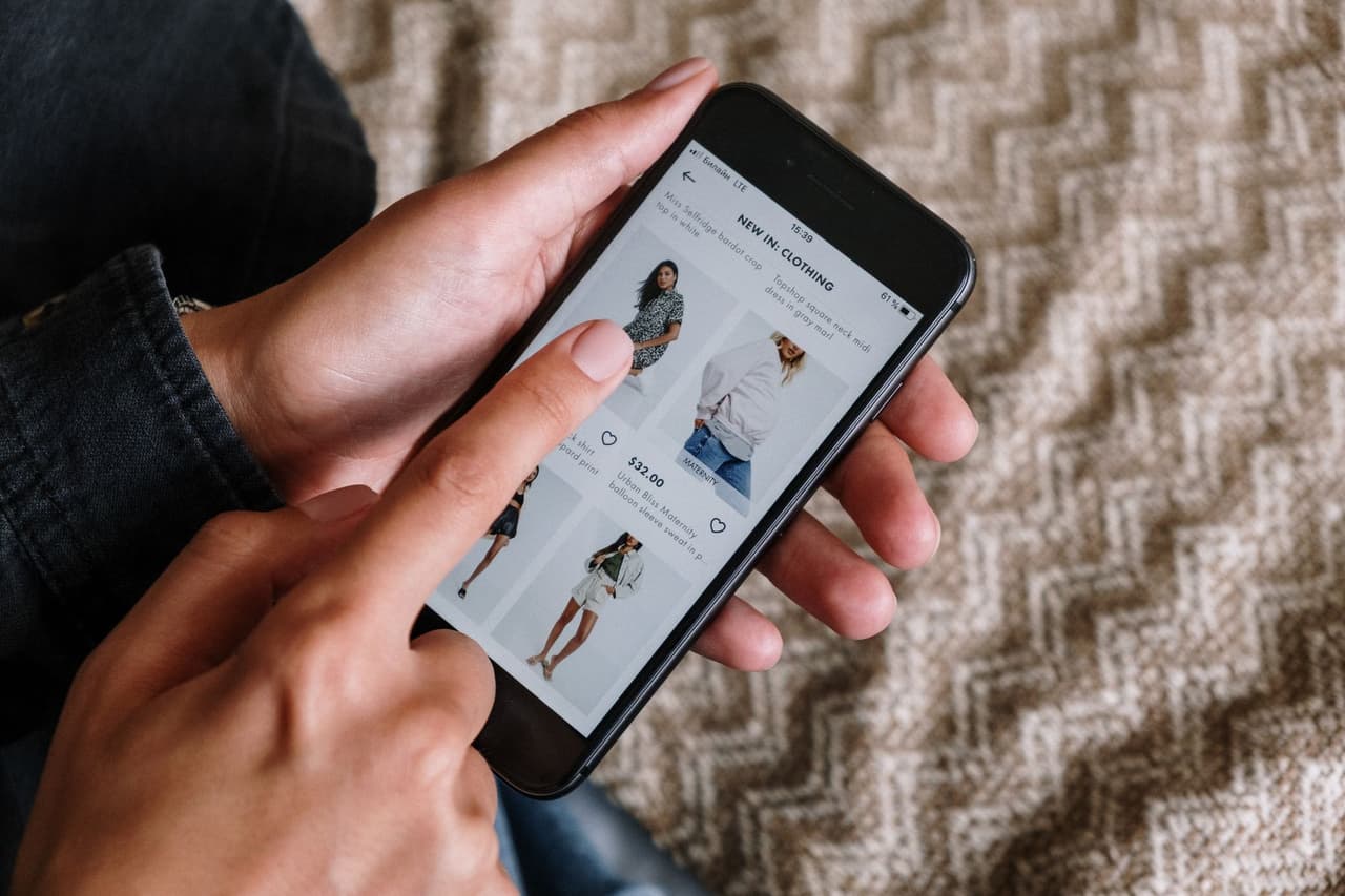 A person choosing an app on a smartphone while shopping online