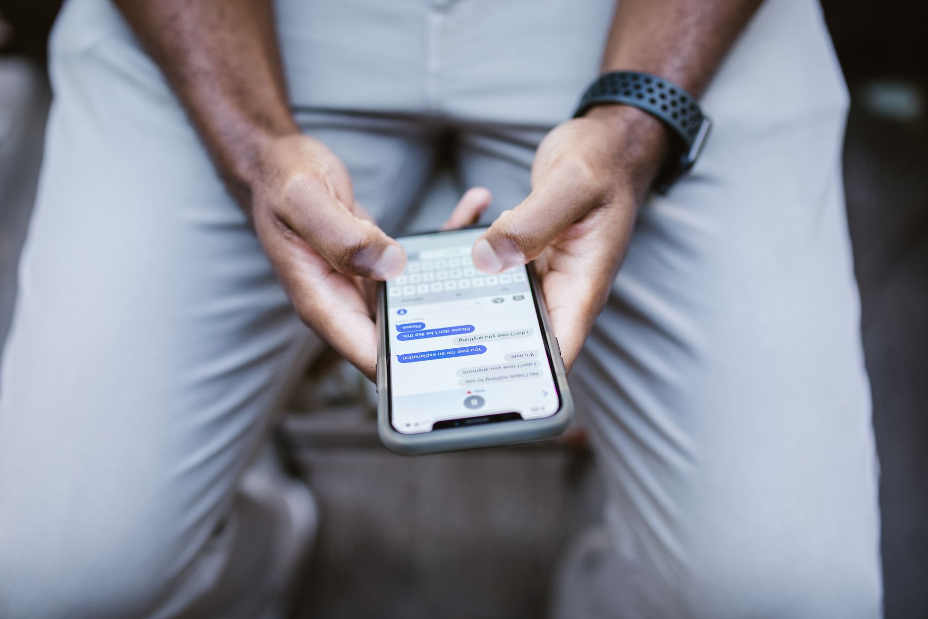 Close-up of a person typing a WhatsApp message on a smartphone at a desk