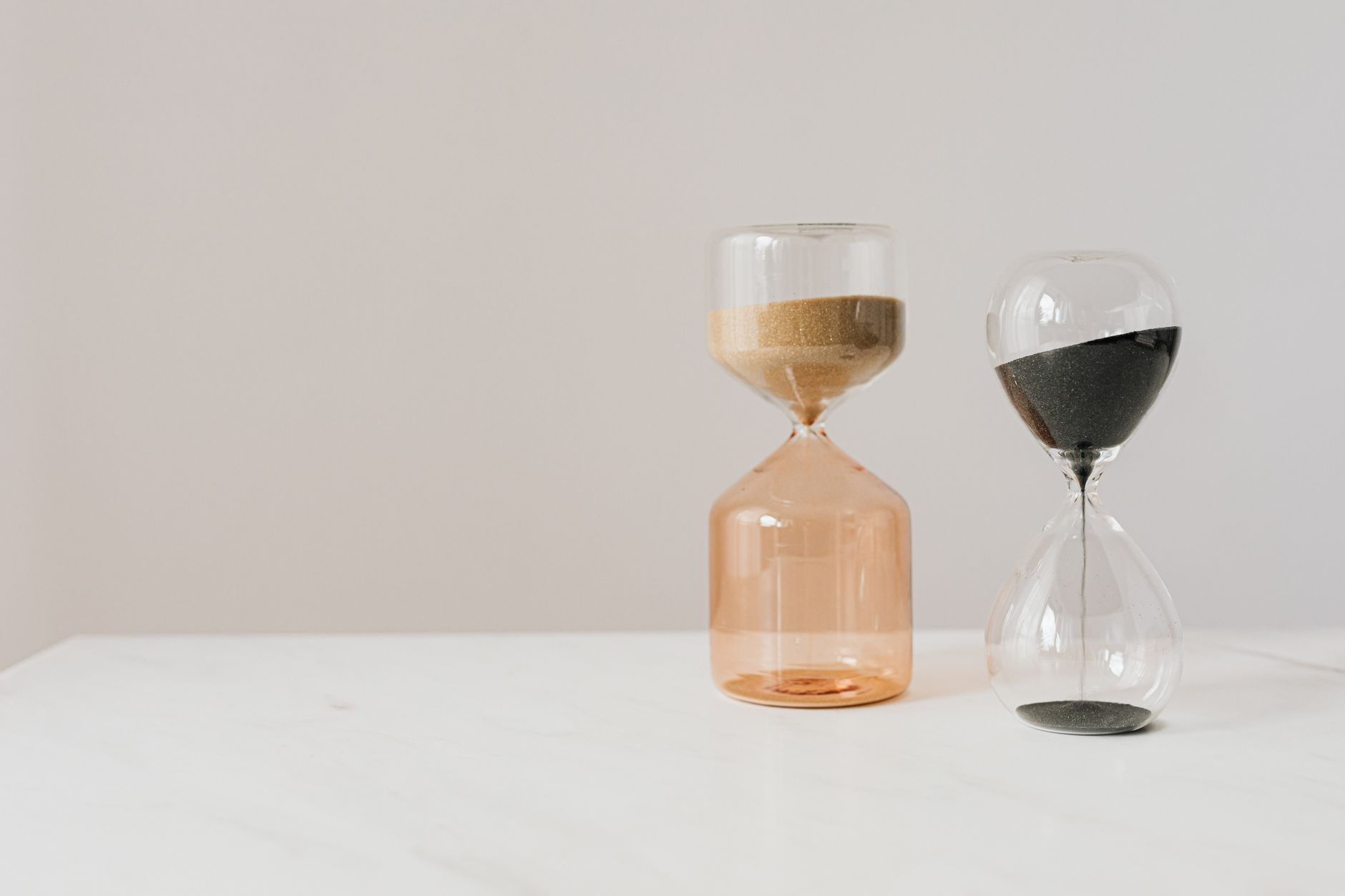 Hourglasses with running sand on a white table, representing a time window