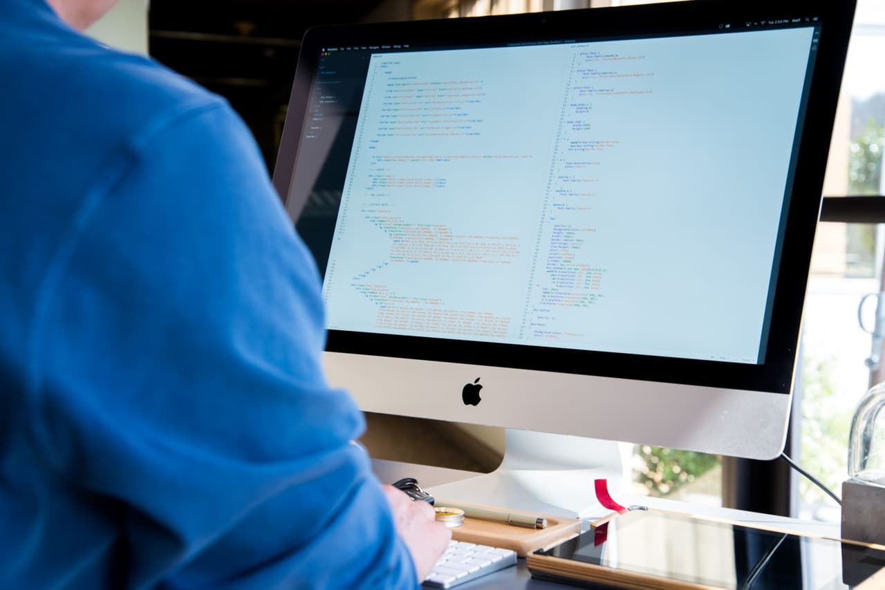 A developer coding on a desktop computer in a bright office