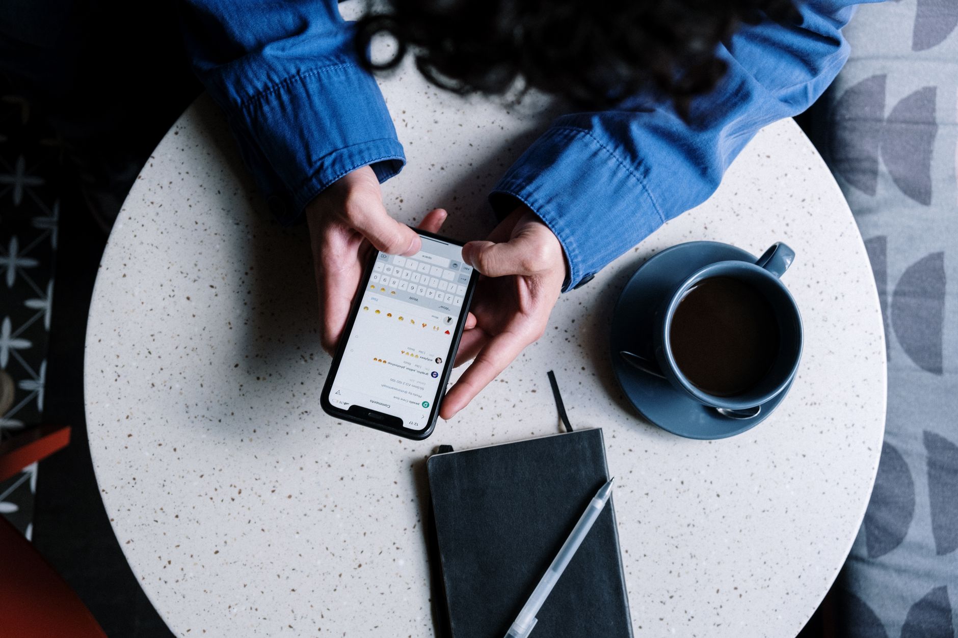 Small business owner replying to a WhatsApp Business message on a smartphone at a café table