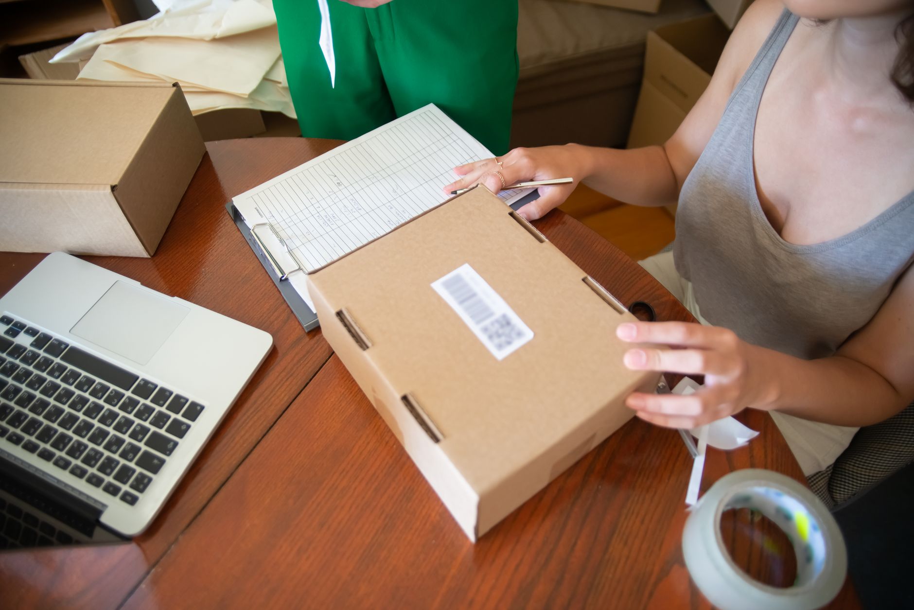 Small business owners packing online orders next to a laptop