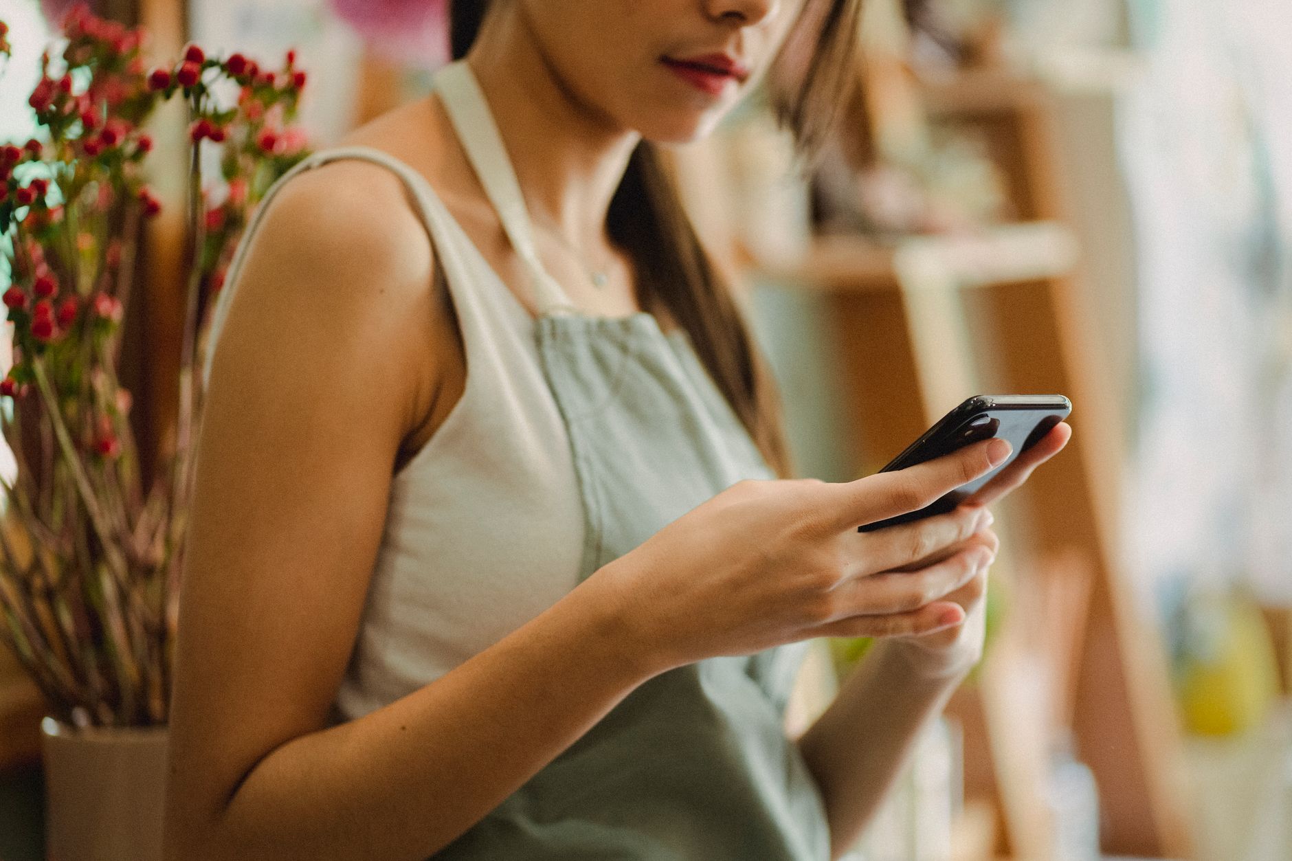 Small business owner checking a smartphone while working in their shop