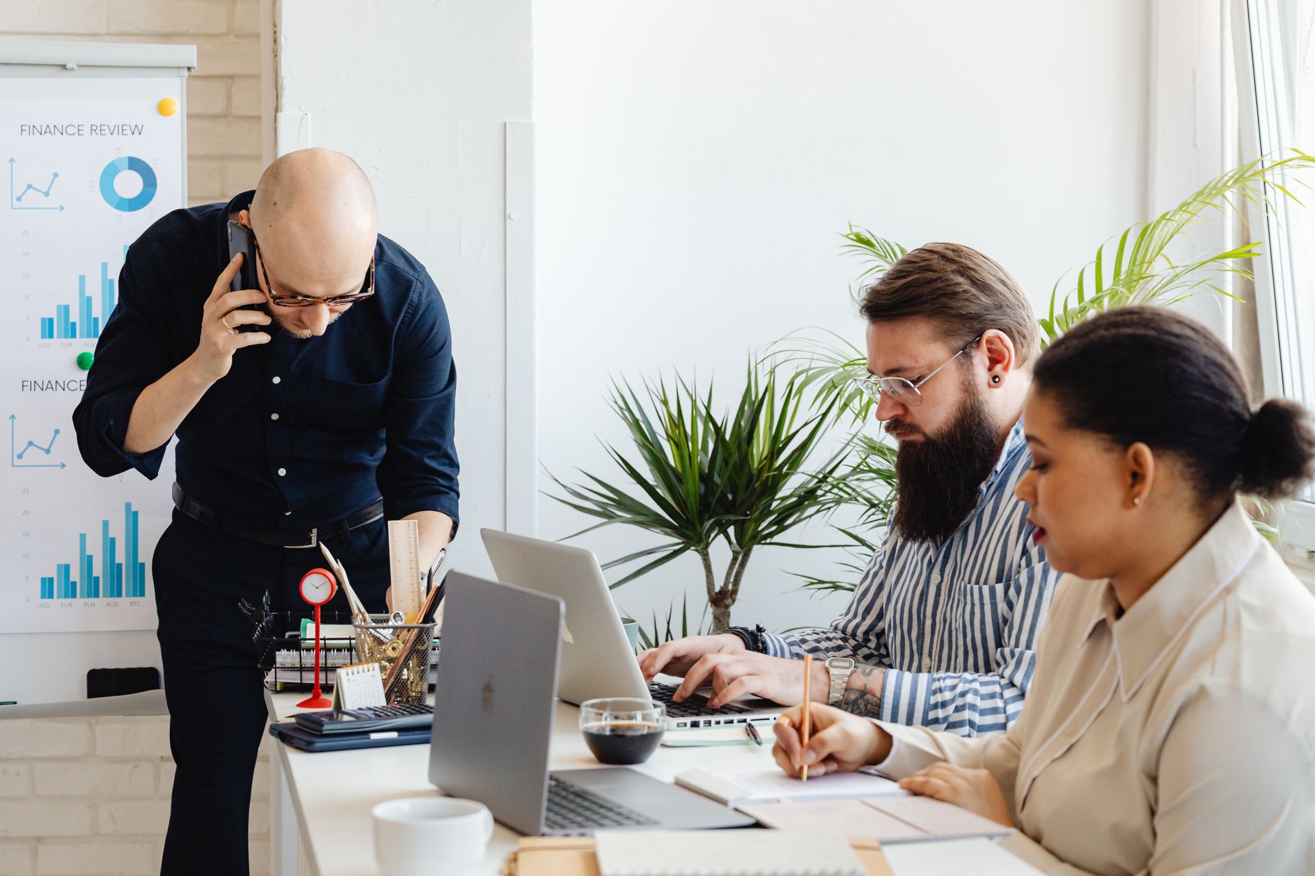 A small team collaborating with laptops and a phone in a modern office