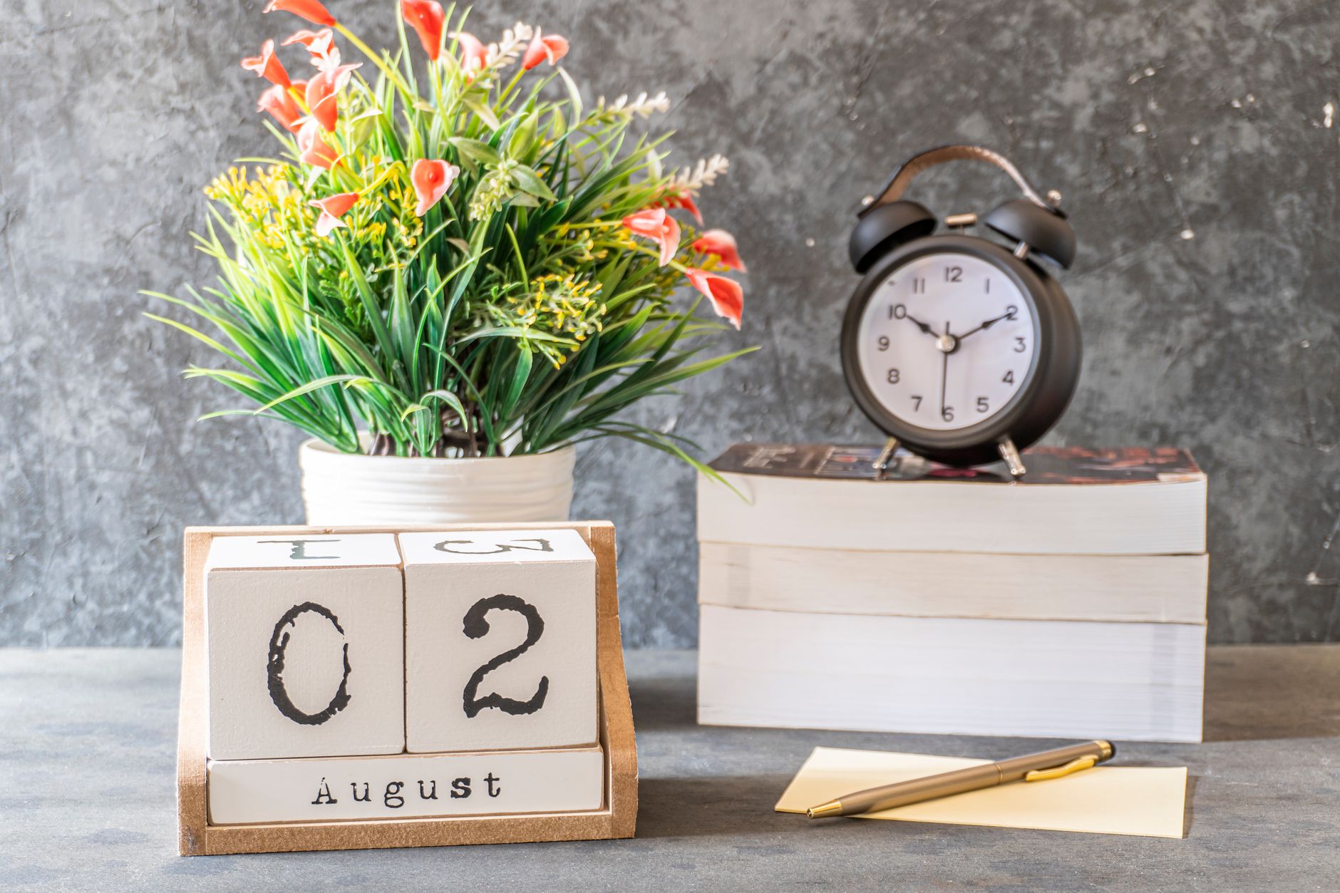 Desk calendar set with a clock, notepad, and flowers for planning ahead