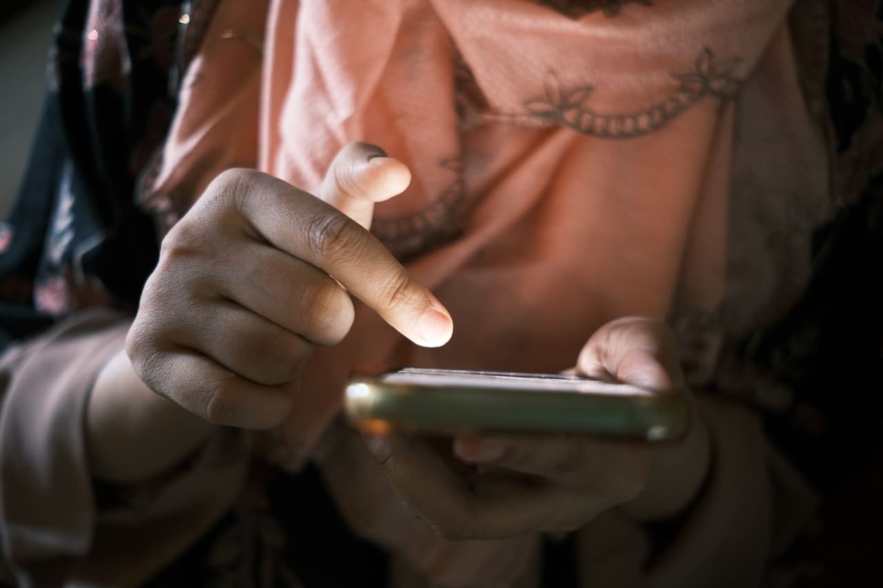 Close-up of hands tapping a smartphone screen