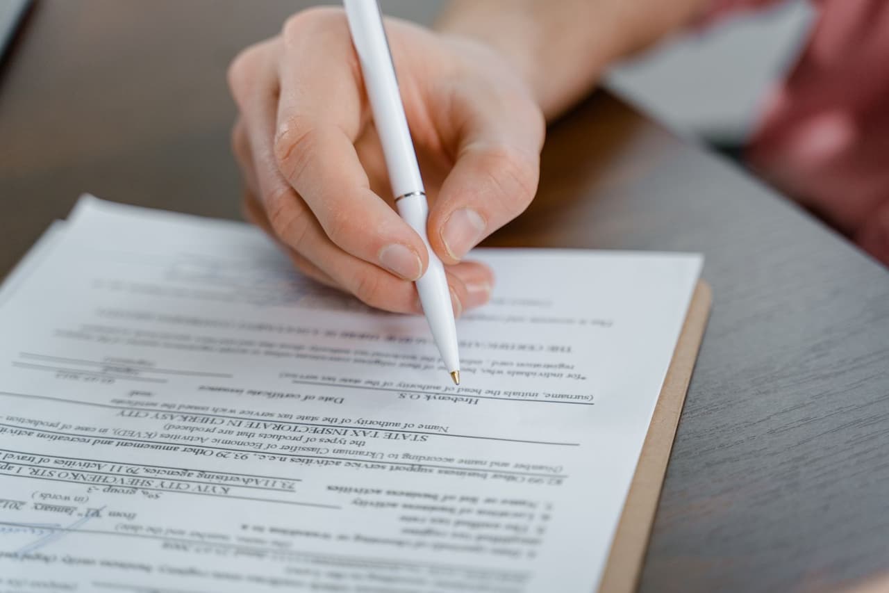 A hand filling out a form with a pen
