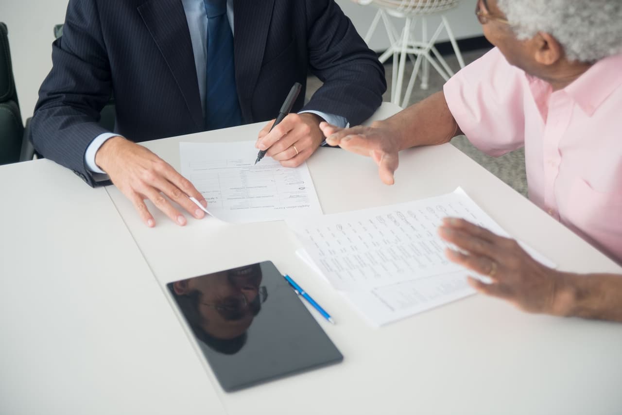 An insurance agent discussing documents with a client at a desk