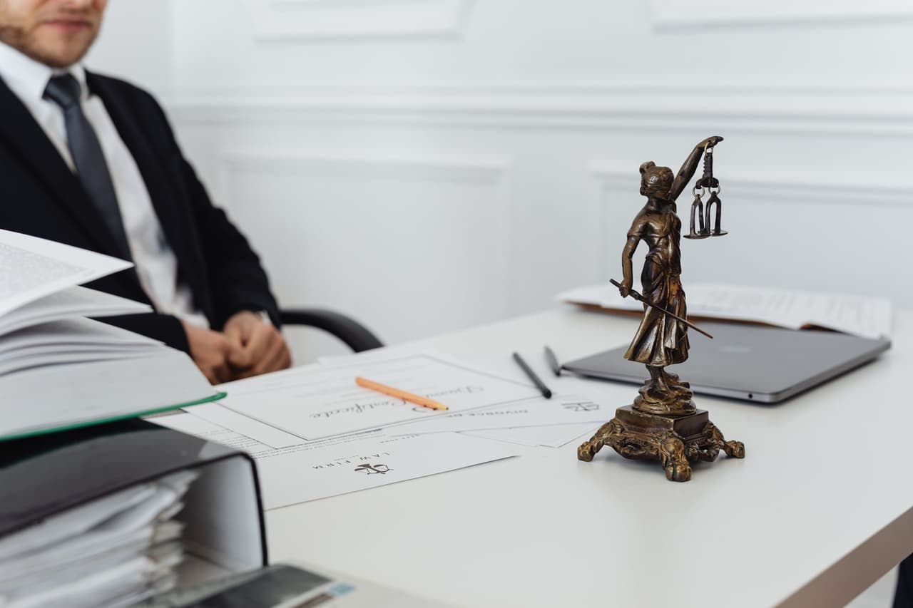 A legal workspace with a Lady Justice statue, documents, and a laptop