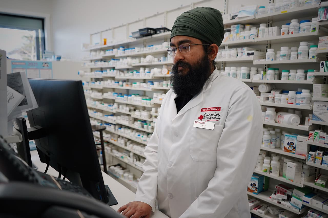 A pharmacist working at a computer in a pharmacy