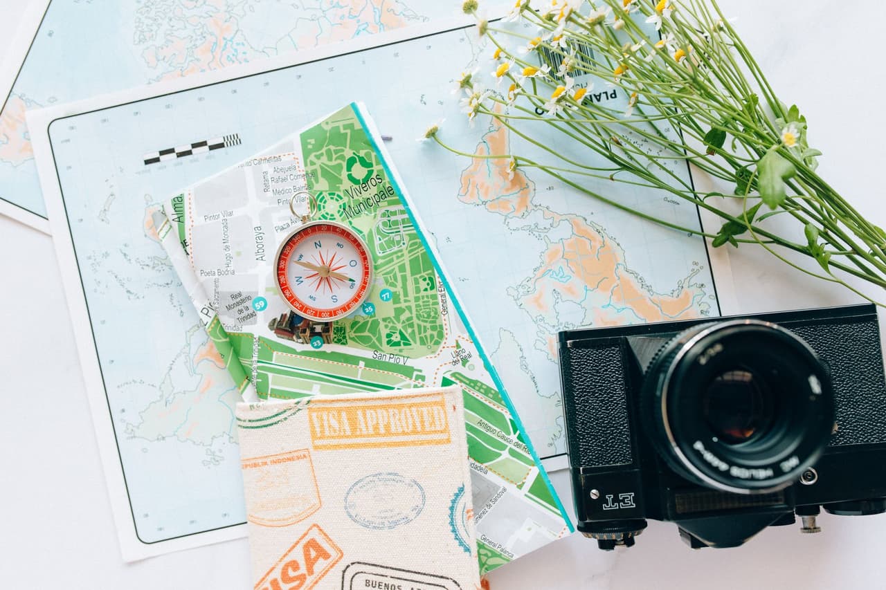 Travel planning items including a map, compass, and vintage camera on a desk