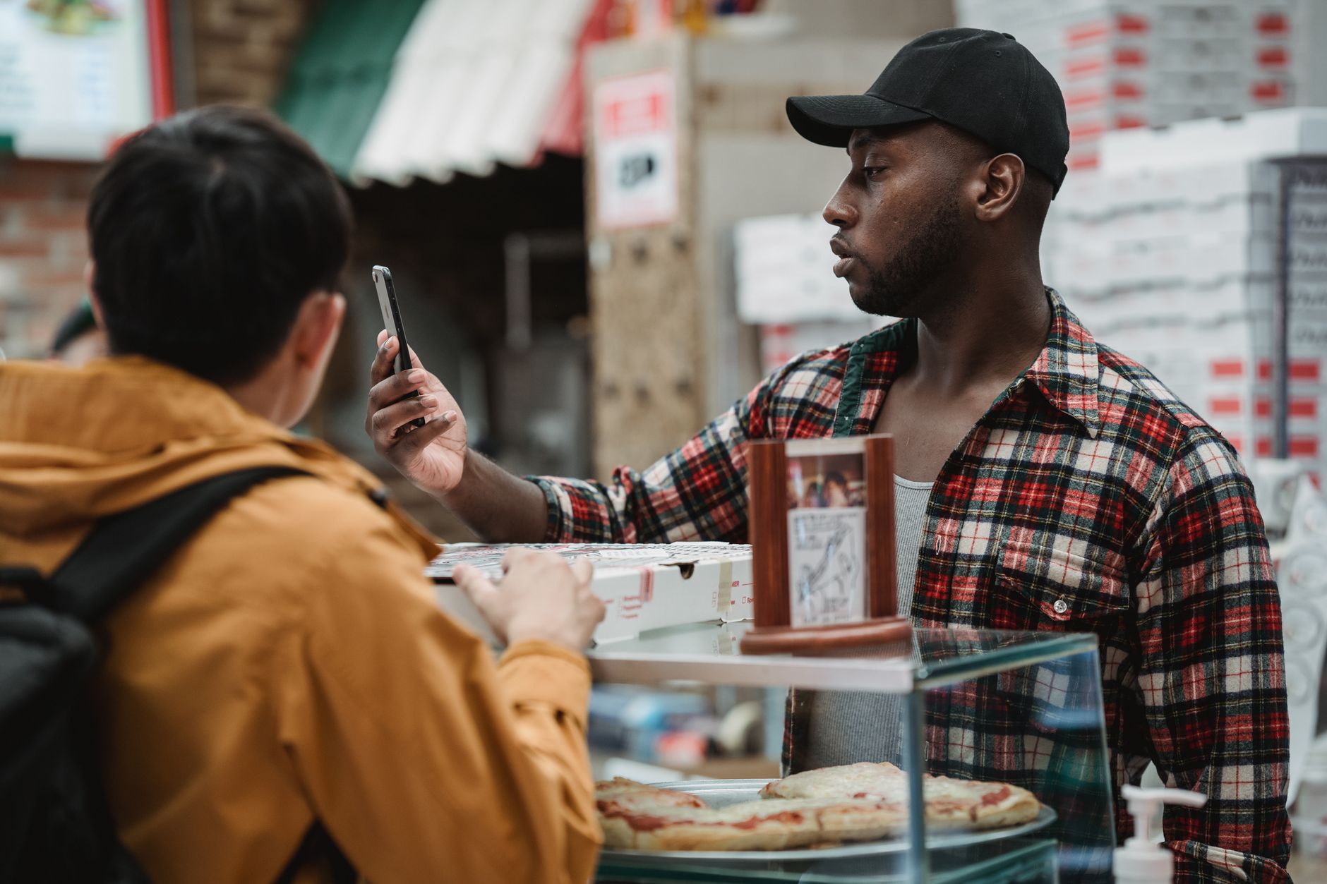 Customer holding a smartphone at a pizzeria counter
