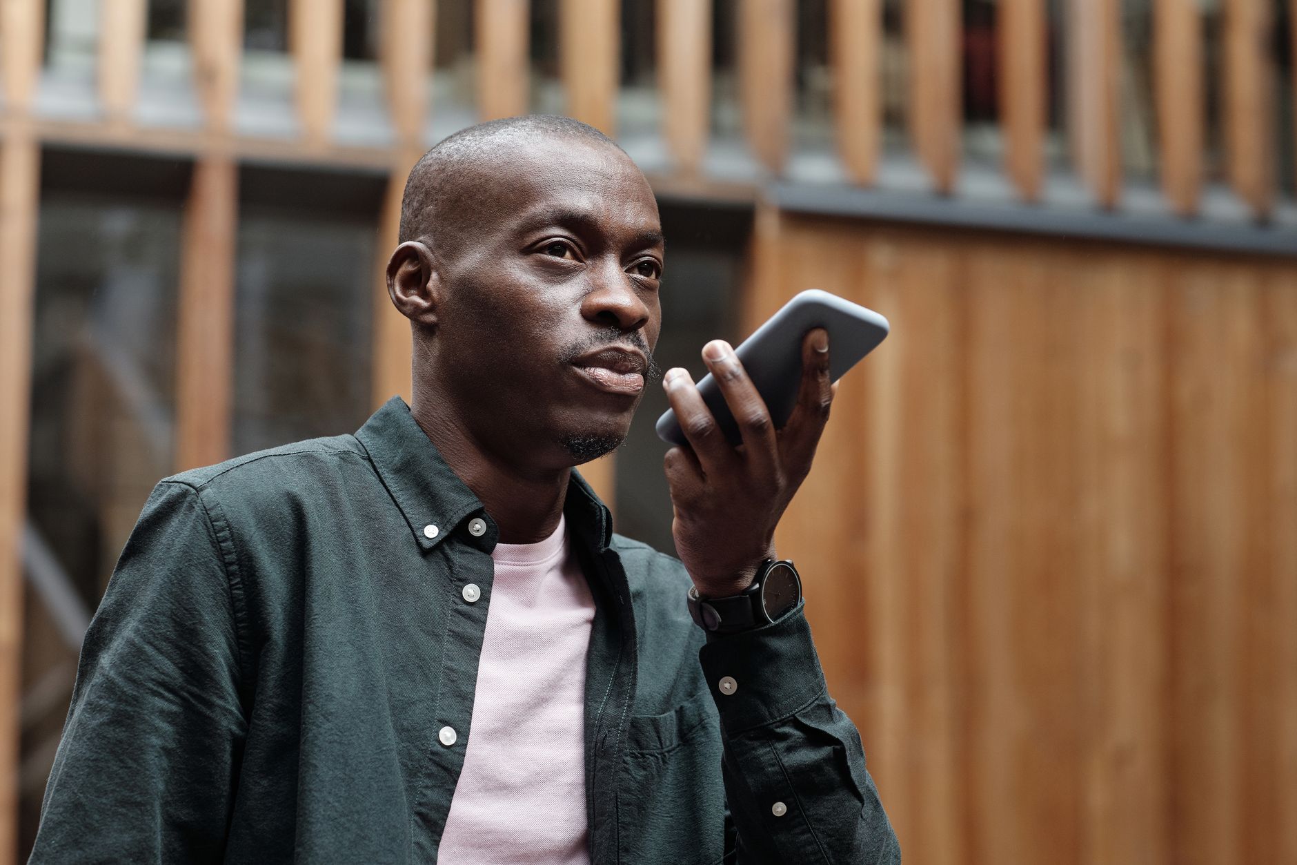 A man speaking a voice message into his smartphone on a city street